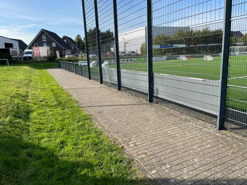 Grünstreifen neben einem befestigten Weg an einem Sportplatz